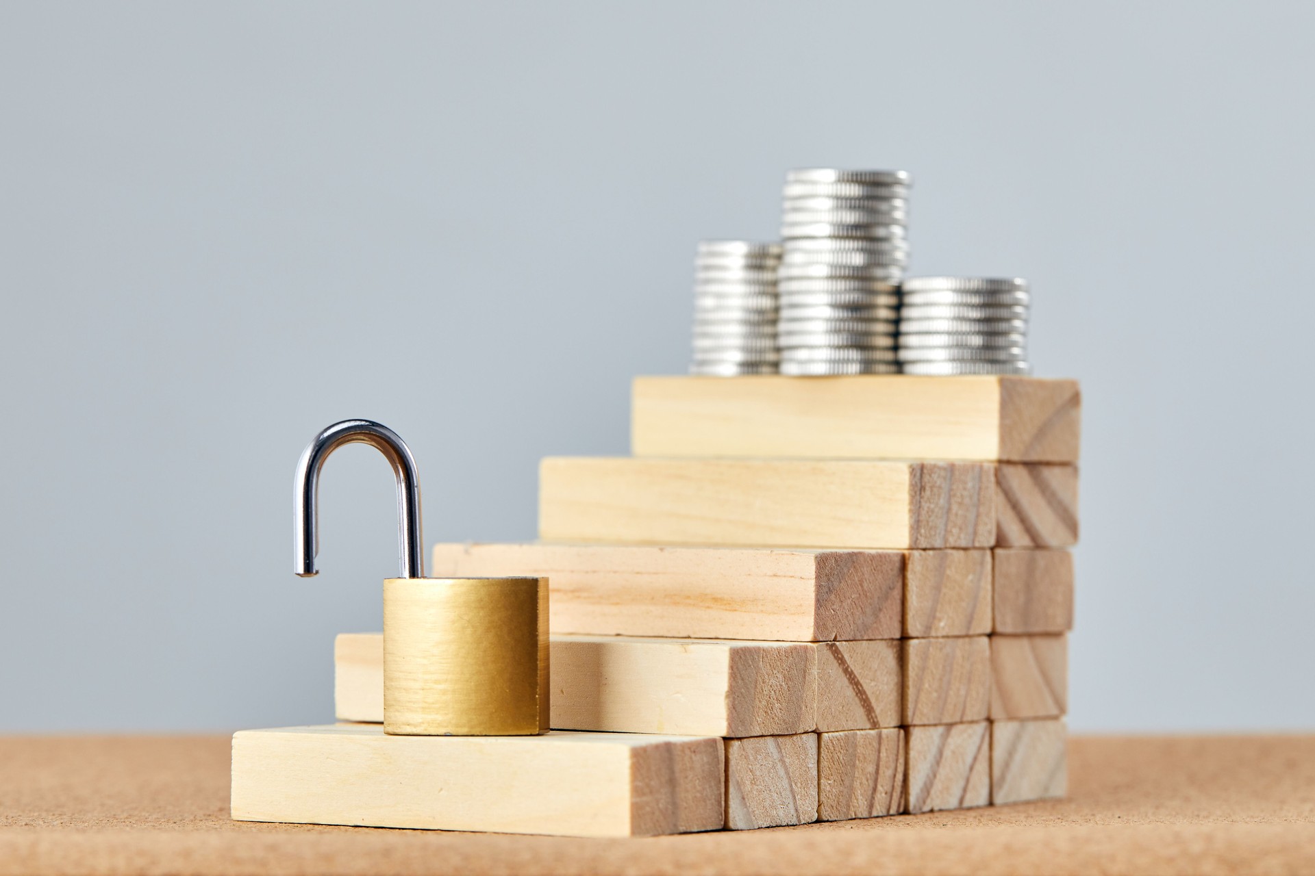 Lifting the ban for business growth. Open lock as a symbol of opportunities for success of money financial. Stairs made by wooden blocks with a coins at the top.